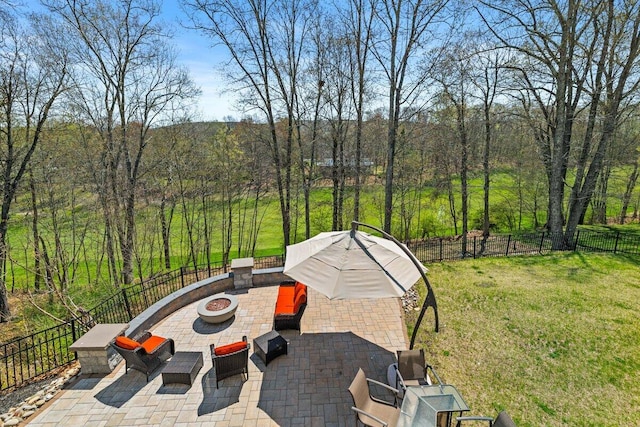 view of patio / terrace with a fenced backyard, a view of trees, and an outdoor fire pit