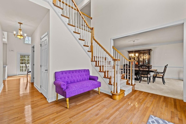 stairs with baseboards, a notable chandelier, and hardwood / wood-style flooring