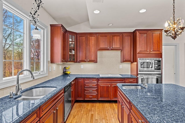 kitchen with light wood-style floors, a sink, appliances with stainless steel finishes, and decorative light fixtures