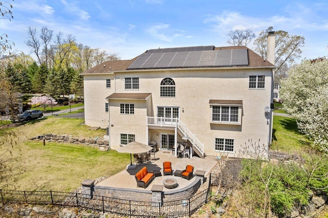rear view of house featuring a fire pit, a patio, a chimney, a yard, and solar panels