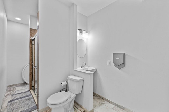 bathroom with baseboards, a shower stall, toilet, and marble finish floor