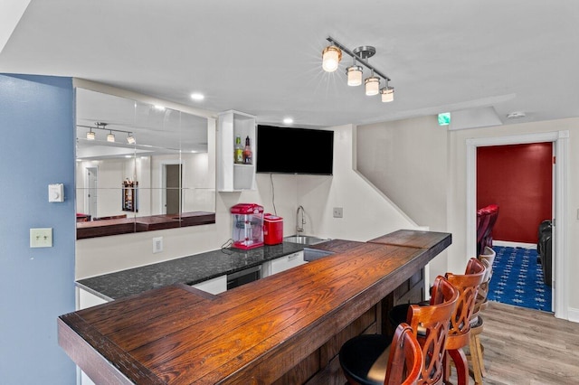 bar featuring indoor wet bar, track lighting, a sink, and light wood finished floors