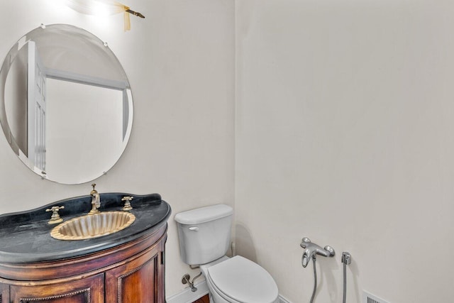 half bath featuring vanity, baseboards, and toilet