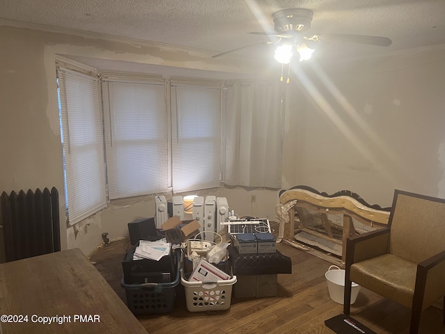 bedroom featuring ceiling fan, a textured ceiling, wood finished floors, and radiator heating unit