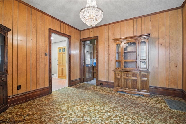 639 Iron St, Lehighton, PA 18235 - unfurnished dining area featuring wood walls, crown molding, a chandelier, a textured ceiling, and carpet floors