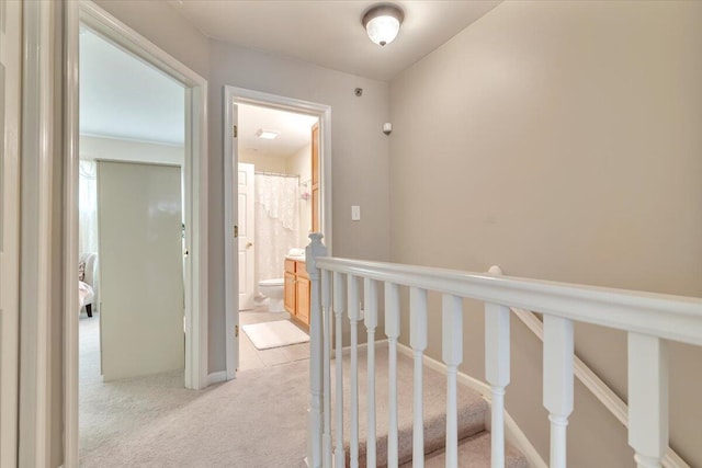 hall with an upstairs landing and light carpet