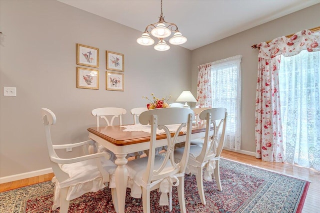 dining area with baseboards, an inviting chandelier, and wood finished floors