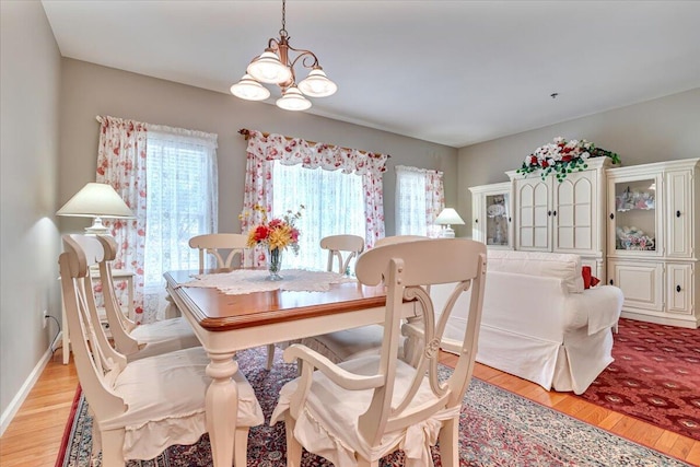 dining space with light wood-style floors and a notable chandelier