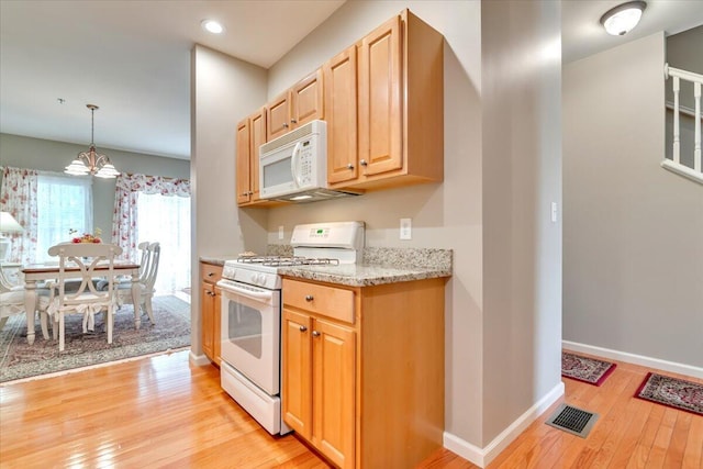 kitchen featuring a notable chandelier, light brown cabinets, white appliances, light wood-style flooring, and baseboards