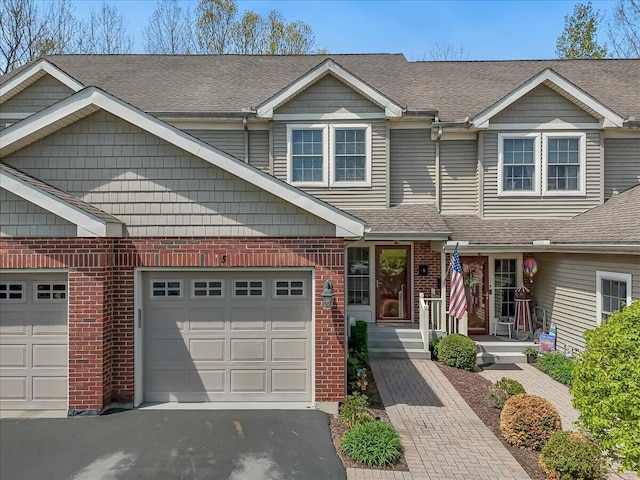 view of front of home with brick siding, an attached garage, roof with shingles, and aphalt driveway