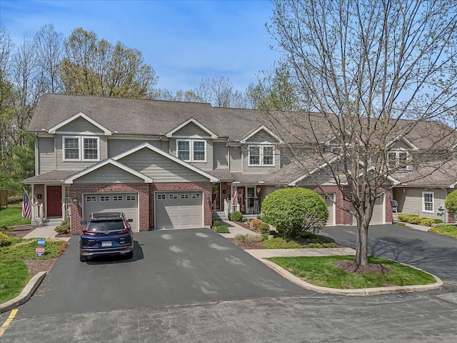 townhome / multi-family property with brick siding, driveway, and roof with shingles