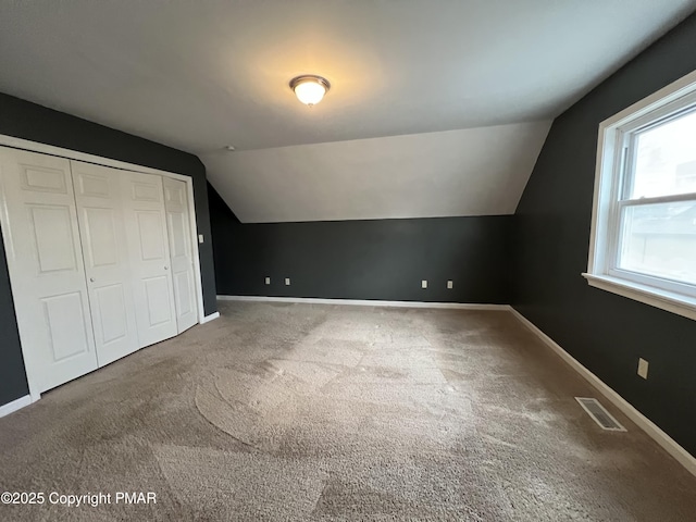 additional living space with carpet, visible vents, baseboards, and vaulted ceiling