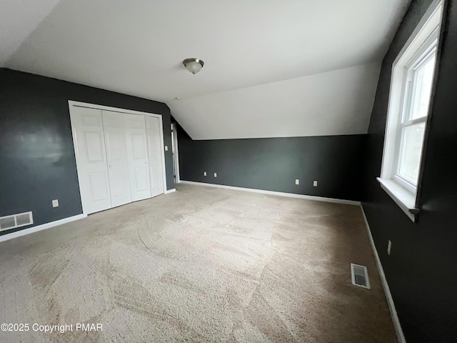 bonus room featuring lofted ceiling, carpet floors, visible vents, and baseboards