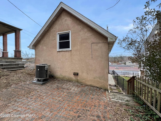 view of property exterior featuring a patio area, fence, central AC, and stucco siding