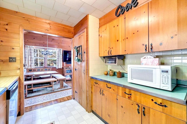 kitchen featuring wooden walls, white microwave, light floors, decorative backsplash, and light countertops