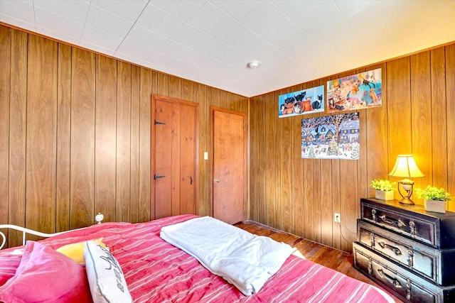 bedroom featuring wood finished floors and wood walls