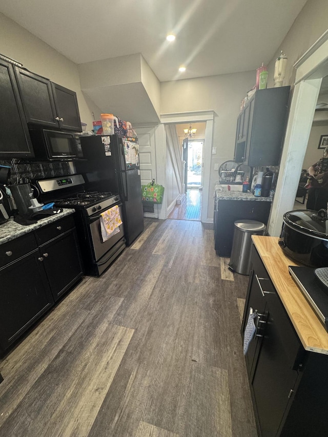 kitchen with black appliances, a notable chandelier, dark cabinets, and dark wood-type flooring