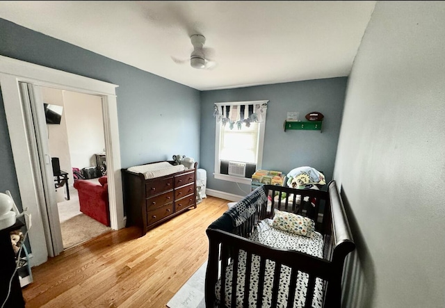 bedroom featuring cooling unit, baseboards, light wood-type flooring, and ceiling fan