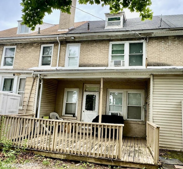 rear view of property featuring a shingled roof, cooling unit, and a chimney