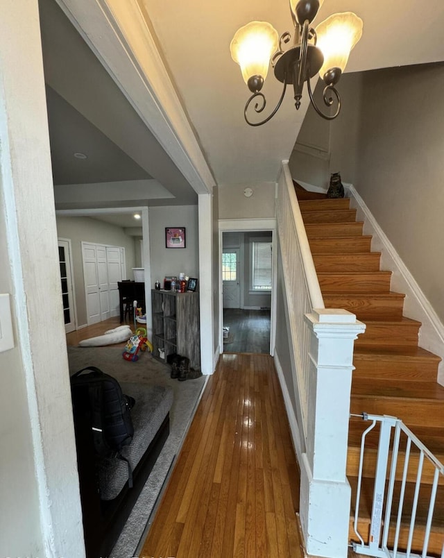 foyer with baseboards, wood-type flooring, a chandelier, and stairs