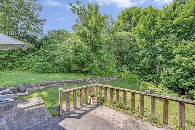 wooden terrace featuring a lawn and a patio