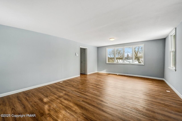 unfurnished room with baseboards and dark wood-style floors