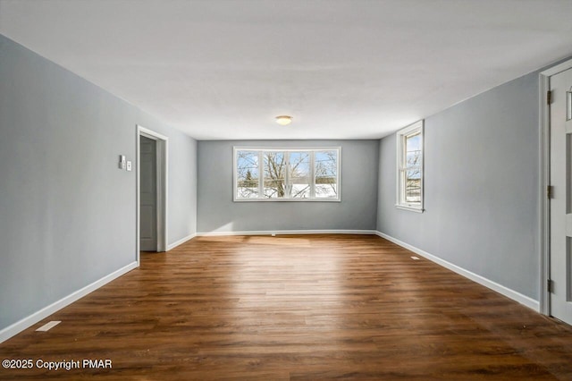 spare room featuring baseboards, plenty of natural light, and wood finished floors