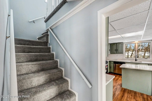 staircase featuring a paneled ceiling and wood finished floors