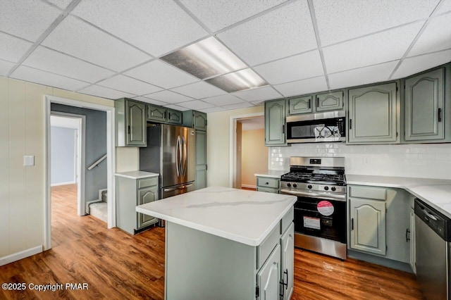 kitchen with green cabinets, decorative backsplash, dark wood-style floors, and stainless steel appliances