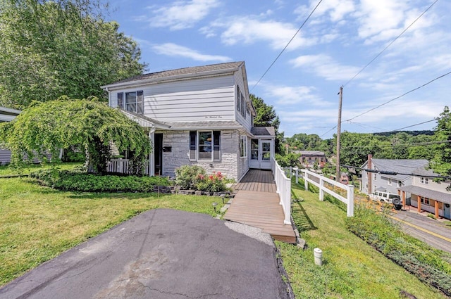 view of front of house featuring stone siding, a front lawn, and fence