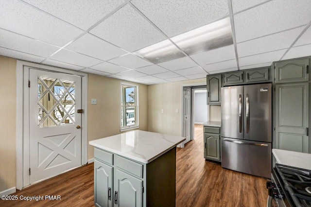 kitchen with a center island, dark wood-type flooring, light countertops, appliances with stainless steel finishes, and a paneled ceiling