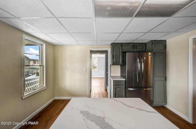 kitchen with a paneled ceiling, light stone countertops, dark wood-style flooring, and freestanding refrigerator