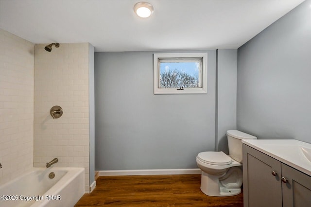 full bath with toilet, wood finished floors,  shower combination, baseboards, and vanity