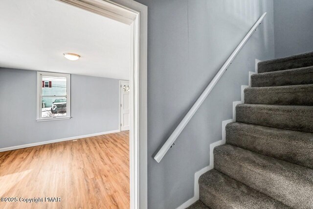 staircase featuring baseboards and wood finished floors