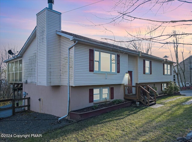 view of front of house featuring stucco siding, a lawn, a sunroom, and a chimney