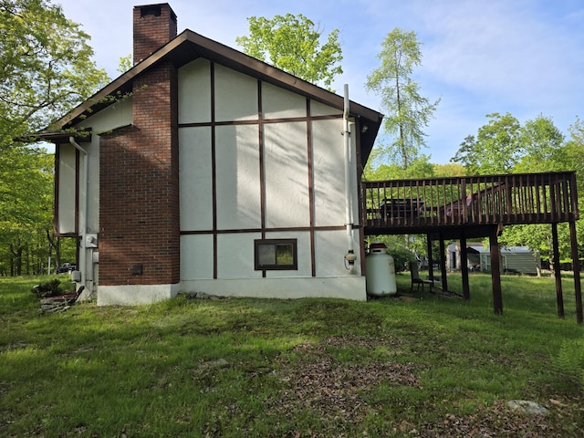 234 Saturn Dr, Bushkill, PA 18324 - view of property exterior featuring a chimney, a deck, a lawn, brick siding, and stucco siding