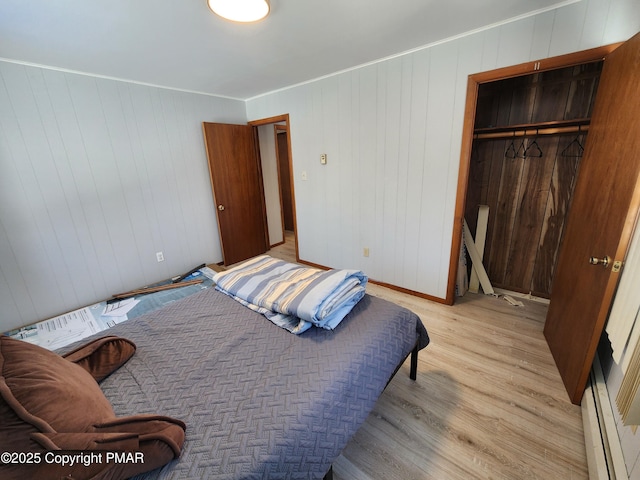 234 Saturn Dr, Bushkill, PA 18324 - bedroom with light wood finished floors, a closet, a baseboard radiator, and wood walls