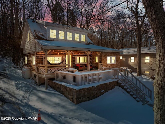 snow covered back of property with covered porch