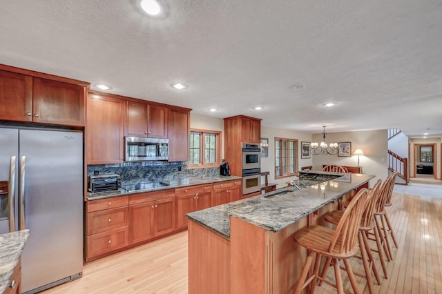 3110 Tall Timber Lake Rd, Pocono Pines, PA 18350 - kitchen featuring appliances with stainless steel finishes, light wood-style floors, a kitchen breakfast bar, a chandelier, and recessed lighting