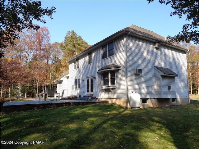 rear view of house featuring entry steps, a lawn, and a patio