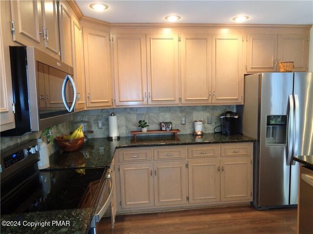 kitchen with dark stone countertops, tasteful backsplash, appliances with stainless steel finishes, and dark wood-style flooring