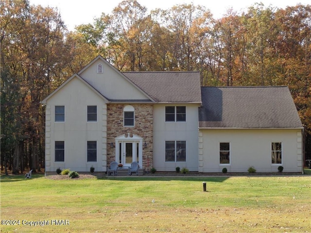 view of front of home with stone siding, a shingled roof, and a front lawn