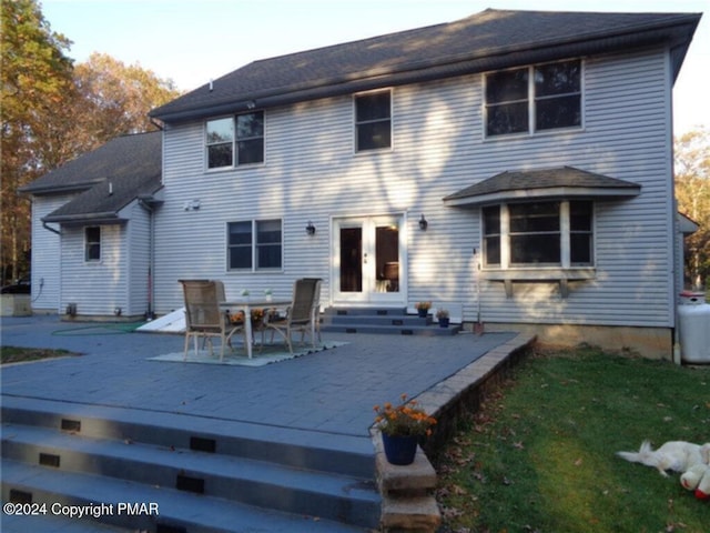 rear view of house with entry steps, a deck, a lawn, and french doors