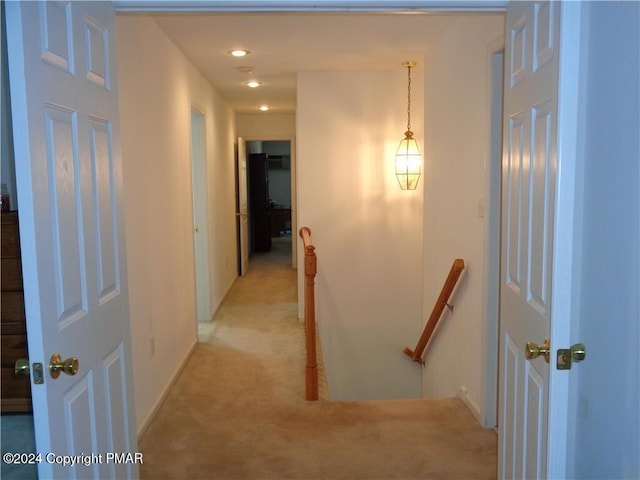 hall with light carpet and an upstairs landing