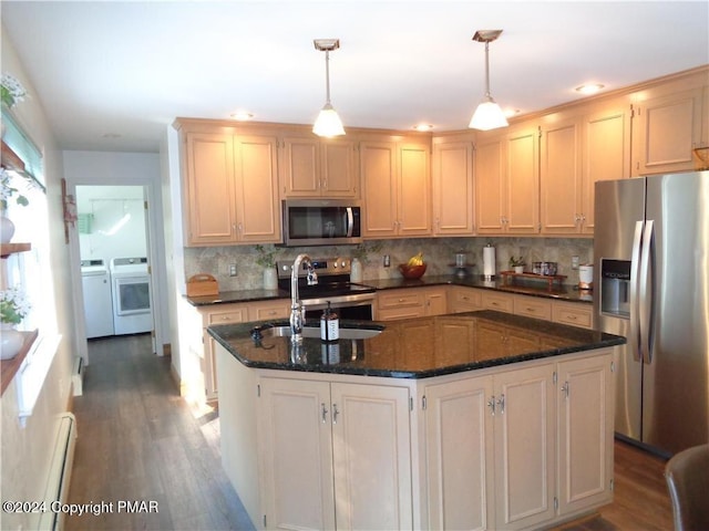 kitchen featuring separate washer and dryer, a sink, appliances with stainless steel finishes, baseboard heating, and an island with sink