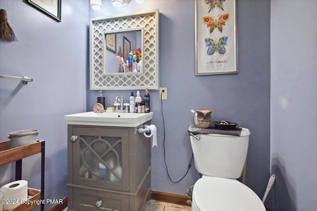 half bathroom featuring baseboards, vanity, and toilet