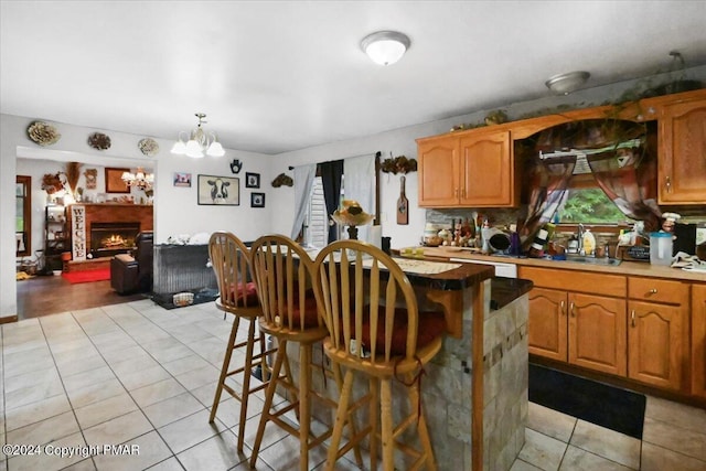 kitchen featuring light tile patterned floors, a breakfast bar area, a sink, a brick fireplace, and a center island