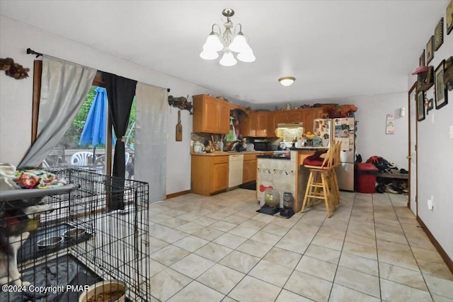 kitchen featuring an inviting chandelier, freestanding refrigerator, light tile patterned flooring, white dishwasher, and under cabinet range hood