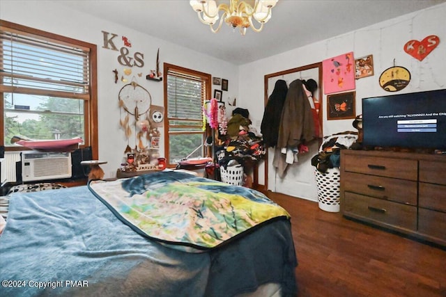 bedroom with cooling unit, a notable chandelier, and wood finished floors