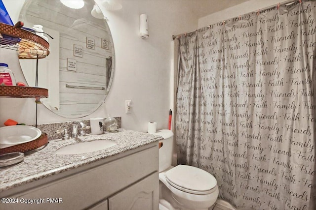 bathroom featuring toilet, curtained shower, and vanity